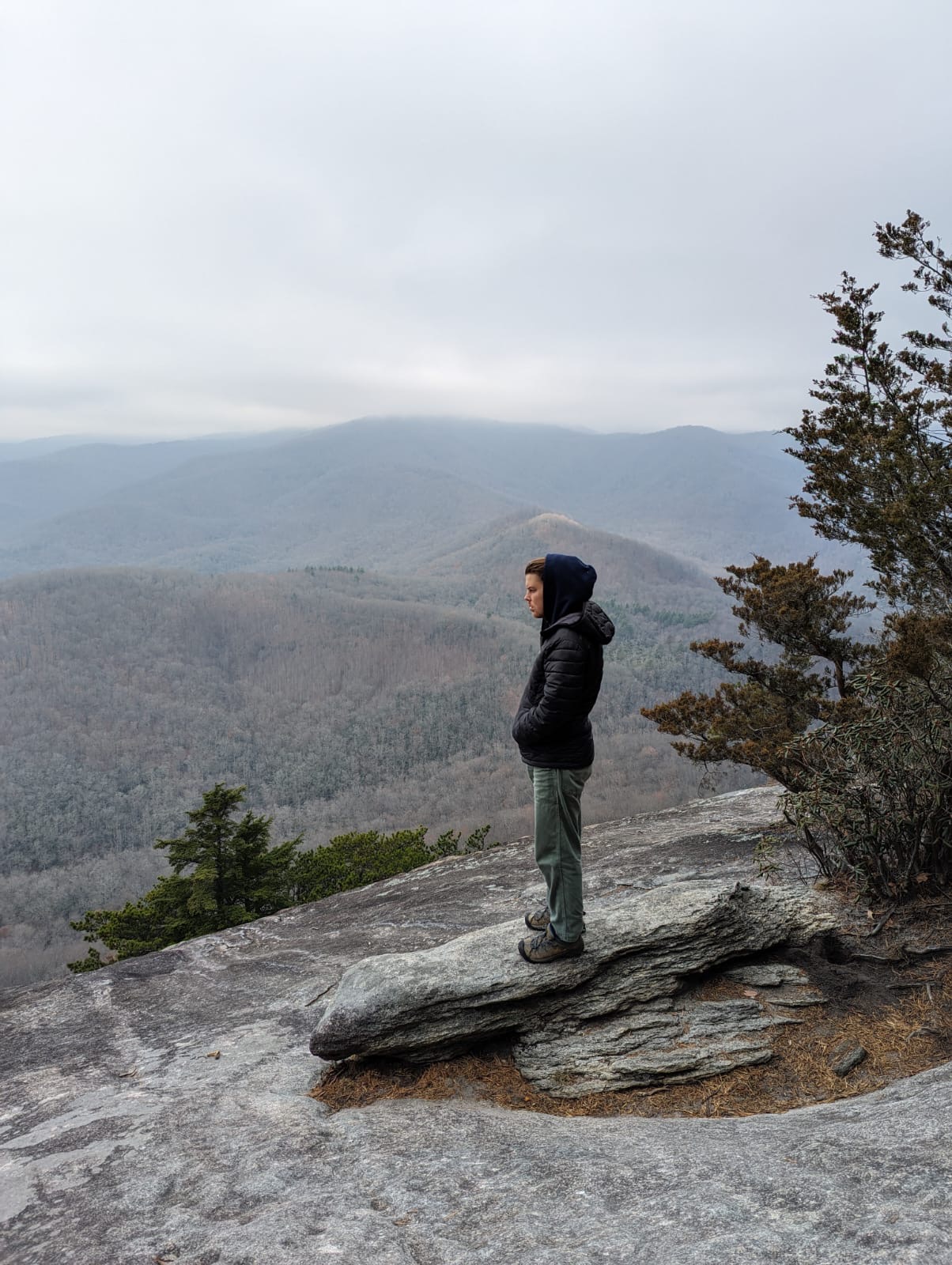Person standing on rock overlooking misty mountains